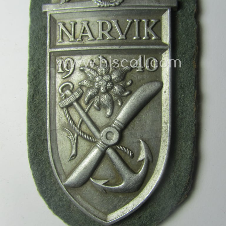 Superb - and scarcely encountered! - WH (KM) 'Narvik'-campaign-shield being a very detailed example as executed in silver-toned zinc- (ie. 'Feinzink') and that comes in an issued- (albeit I deem never worn- nor tunic-attached-), condition