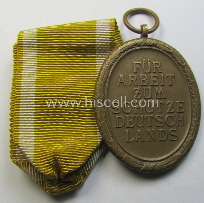Medal-set: 'Deutsches Schutzwall Ehrenzeichen' (aka: 'Westwall'-medal) being a non-maker-marked- and/or: 'Buntmetall'-based specimen that comes together with its period- (and neatly folded ie. pre-confectioned) ribbon (ie. 'Bandabschnitt')