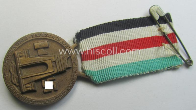 Golden-bronze-coloured- (and I deem 'Buntmetall'-based-) example of a: 'Deutsch-Italienische Feldzugsmedaille' (or: German-Italian campaign-medal) that comes mounted onto its (regular-sized) piece of original (and hardly faded!) ribbon