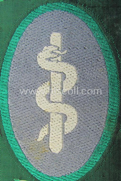 Attractive, 'Sicherheits- u. Hilfsdienst' (ie. 'SHD'-) armbadge (ie. 'Ärmelabzeichen') being a greyish-coloured example depicting an: 'Aesculapus'-symbol as was intended for a: 'Feldscher' (ie. medical SHD-staff-member)