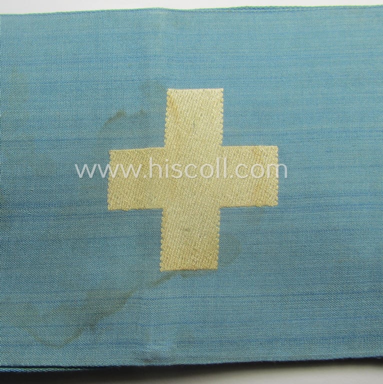 Linnen-based- and/or light-blue-coloured armband (ie. 'Armbinde') depicting an interwoven white-toned cross as was intended for usage by a: 'Sanitäter o. Feldscher des Reichsluftschutz-Bundes'