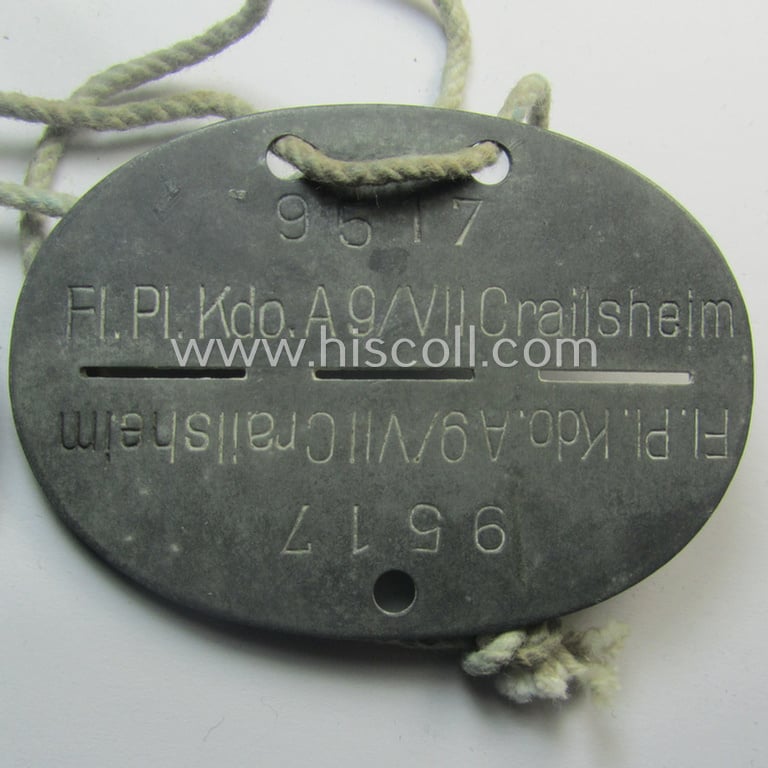 Attractive - and typical zinc-based - WH (Luftwaffe) related ID-disc (ie. 'Erkennungsmarke') bearing the stamped unit-designation that simply reads: 'Fl.Pl.Kdo. A9/VII Crailsheim' and that comes mounted onto its period cord as issued and/or worn