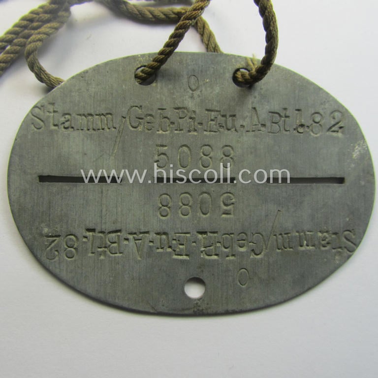 Zinc-based, WH (Heeres) 'Gebirgsjäger-Pioniere'-related ID-disc bearing the clearly stamped unit-designation that reads: 'Stamm. Geb.Pi. E.u.A. Btl. 82' and that comes as issued and/or worn