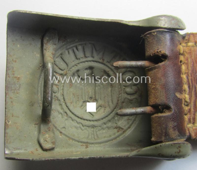 Minimally used, WH (Heeres) field-grey-coloured- and/or steel-based belt-buckle being a clearly maker-marked example that comes mounted onto its maker- (ie. 'Schmöle & Comp - Menden'-) marked and/or '1941'-dated leather-based tab