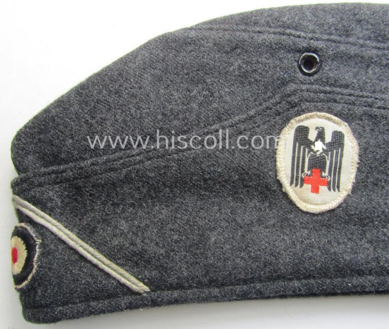 Darker-greyish-blue-coloured, so-called: German Red Cross (ie. 'Deutsches Rotes Kreuz' or: 'DRK' EM- (ie. NCO-) type side-cap (ie. 'Schiffchenmütze für Mannschaften u. Uffz. des deutschen Rotes Kreuzes')