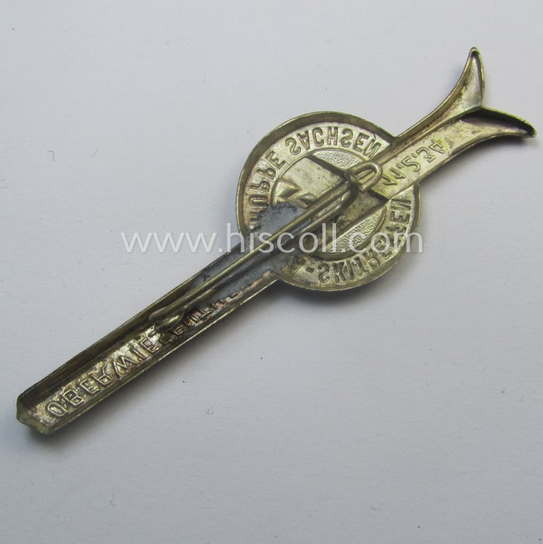 Commemorative, silverish- (ie. golden-orange-) coloured 'SA- o. Sturmabteilungen'-related 'tinnie' being a non-maker-marked example showing a pair of ski's, SA-logo- and text: 'SA-Skitreffen - Gruppe Sachsen - Oberwiesenthal - 11.2.1934'