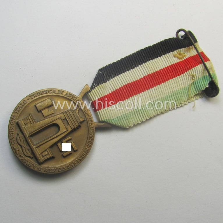 Golden-bronze-coloured- (and I deem 'Buntmetall'-based-) example of a: 'Deutsch-Italienische Feldzugsmedaille' (or: German-Italian campaign-medal) that comes mounted onto its (regular-sized) piece of original (and somewhat faded!) ribbon