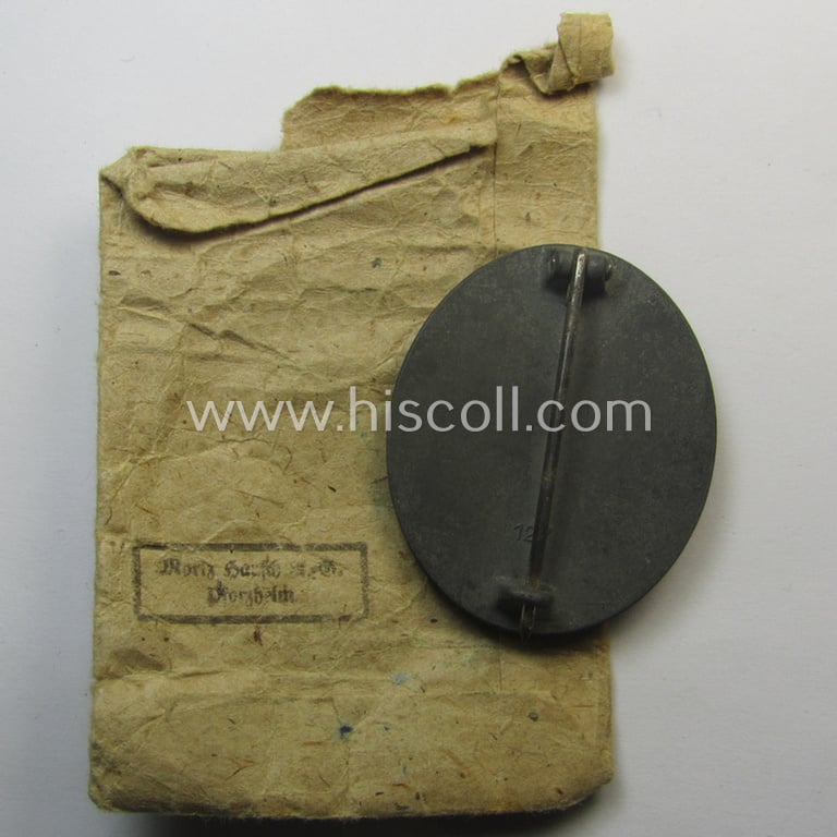 Unusual, silver-class wound-badge (or: 'Verwundeten-Abzeichen in Siber') being a maker- (ie. '127'-) marked example that comes stored in its original (damaged), carton-based pouch by the maker (ie. 'Hersteller'): 'Moriz Hausch A.-G.'