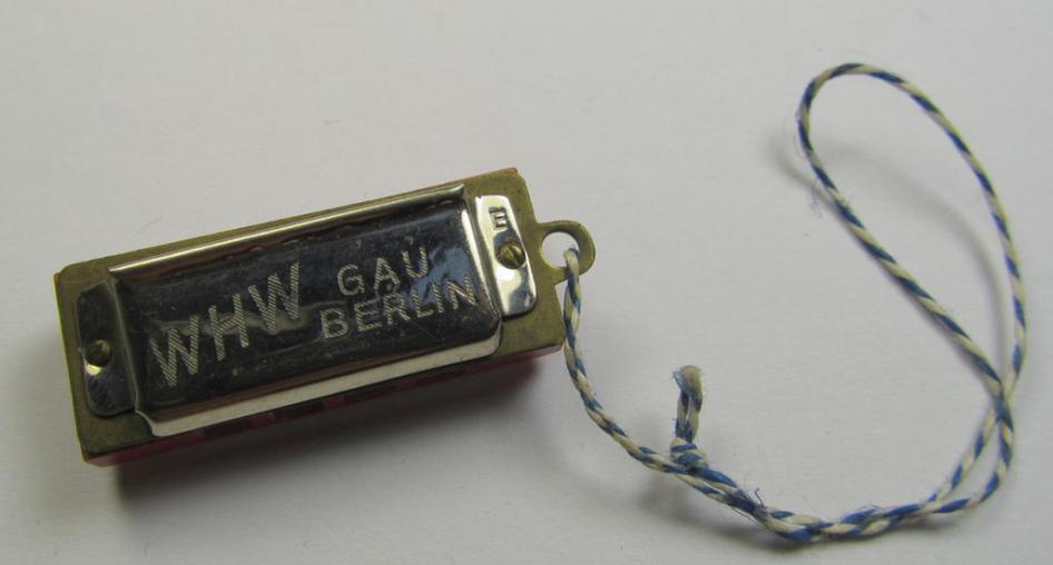 Unusally seen so-called: WHW- (ie. 'Winterhilfswerke'-) related miniature harmonica entitled: 'WHW - Gau Berlin' that comes mounted on its original cord