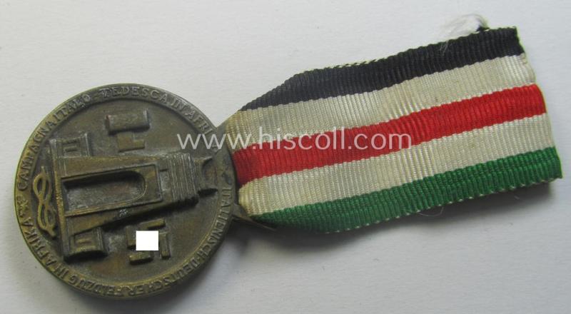 Golden-bronze-coloured (and zinc-based!) example of a: 'Deutsch-Italienische Feldzugsmedaille' (or: German-Italian campaign-medal) that comes mounted onto its (regular-sized) piece of original (and minimally faded- ie. stained!) ribbon