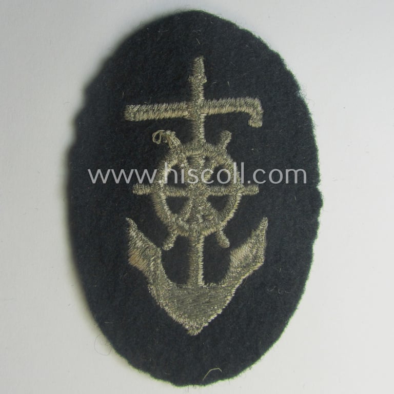 Neat, WH (Heeres) trade- and/or special-career insignia, being a detailed- and/or neatly machine-embroidered example as executed on darker-green-coloured wool as was intended for a: 'Steuermann' (ie. enigineer-boat-pilot or helmsman)