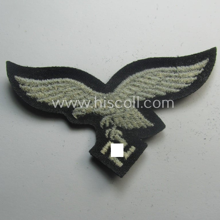 WH (Luftwaffe) cap-eagle (being a 'standard-issue'-pattern example that is executed onto a black-coloured background and that was as such intended for usage on the black-coloured work- ie. 'HG'-related side-caps ie. 'Schiffchen')