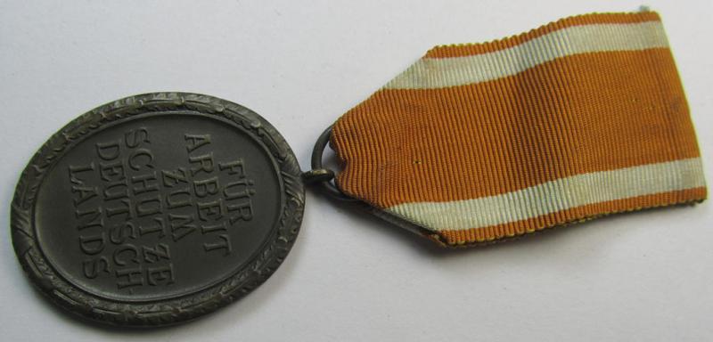Medal-set: 'Deutsches Schutzwall Ehrenzeichen' (aka: 'Westwall'-medal) being a non-maker-marked- and/or: 'Buntmetall'-based specimen that comes mounted onto its period- (and neatly folded ie. pre-confectioned) ribbon (ie. 'Bandabschnitt')