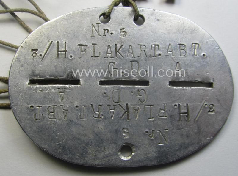 Zinc-based WH (Heeres) 'Heeres-Flak'- ie. 'GrossDeutschland-Division'-related ID-disc bearing the clearly stamped unit-designation that reads: '3./H.FlakArt.Abt. G.D.' and that comes mounted onto its period cord as worn