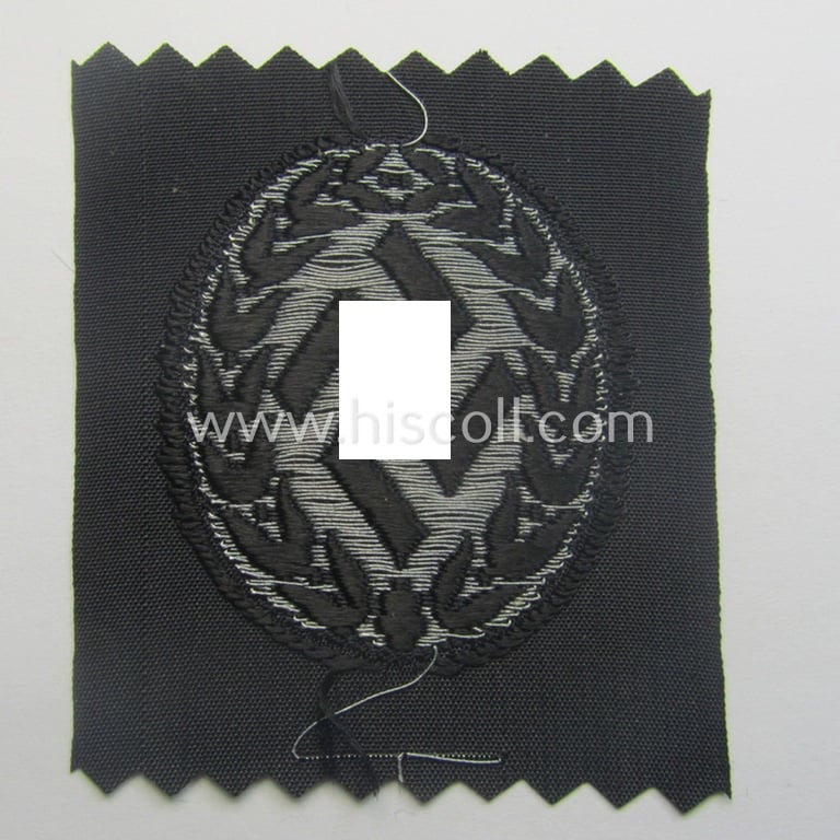 Officer's- (ie. evt. NCO-) type, so-called: 'Schutzmannschaften' (or: 'Schuma') cap-badge as executed in greyish-silver-coloured (so-called: BeVo 'flat-wire'-woven!) thread onto a black-coloured- (ie. 'SS-Polizei'- ie. 'SD'-related-) background