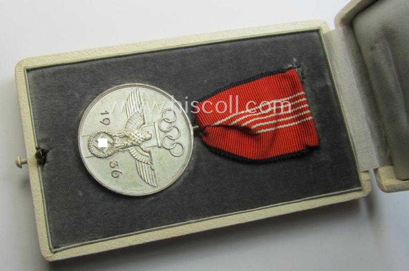 'Deutsche Olympia-Erinnerungsmedaille 1936' being a non-maker-marked example that comes mounted onto its original ribbon (ie. 'Bandabschnitt') and that comes stored in its typical, beige-white-coloured etui