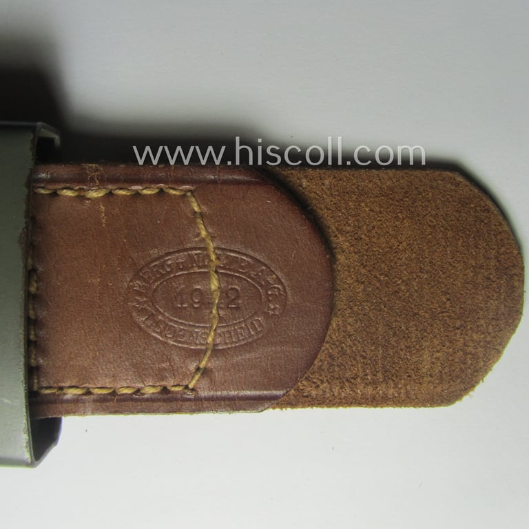 WH (Heeres) 'standard-pattern', field-grey-toned- and steel-based belt-buckle being a maker- (ie. 'Berg u. Nolte - Lüdenscheid'-) marked- and/or: '1942'-dated example that comes mounted onto its leather-based tab