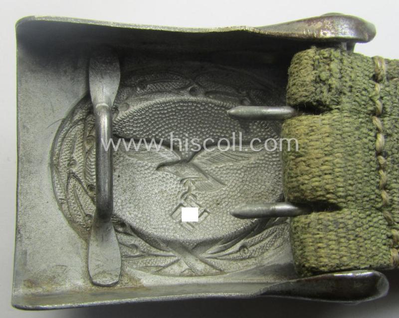 WH (Luftwaffe) 'tropical-issued' belt-buckle being a non-maker-marked, greyish-silver-coloured example that comes mounted onto its original, greenish-coloured- (and/or: 'webbing'-based-) tab