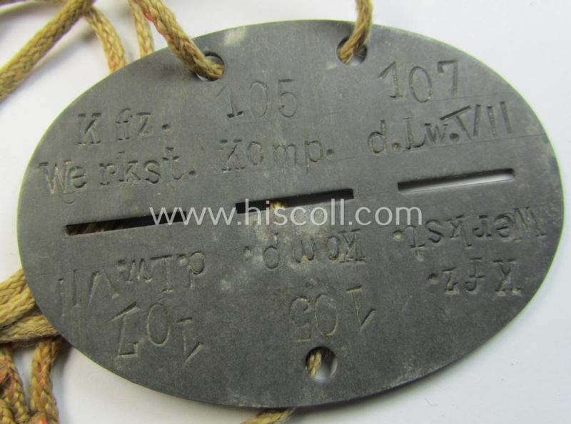 Attractive - and typical zinc-based - WH (Luftwaffe) related ID-disc (ie. 'Erkennungsmarke') bearing the stamped unit-designation that simply reads: 'Kfz.Werkst.Komp.der Lw.VII 107' and that comes mounted onto its period cord as issued & worn