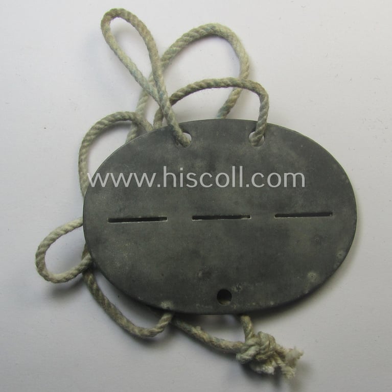 Attractive - and typical zinc-based - WH (Luftwaffe) related ID-disc (ie. 'Erkennungsmarke') bearing the stamped unit-designation that simply reads: 'Fl.Pl.Kdo. A9/VII Crailsheim' and that comes mounted onto its period cord as issued and/or worn