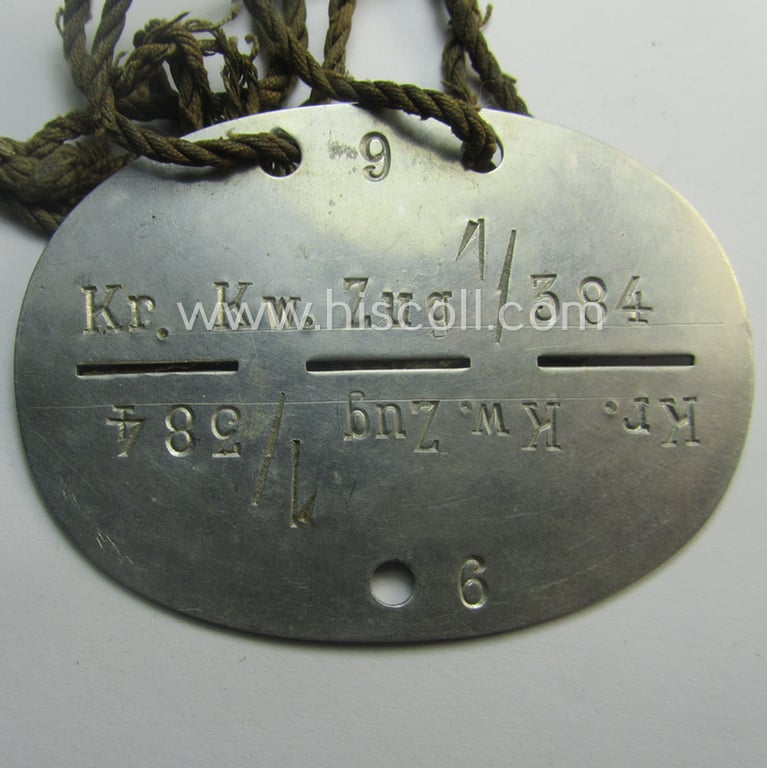 Aluminium-based, WH (Heeres) medical- (ie. 'Sanitäter'-) related ID-disc, bearing the clearly stamped unit-designation: 'Kr.Kw.Zug 1/384' and that comes mounted onto its period cord as issued and/or worn