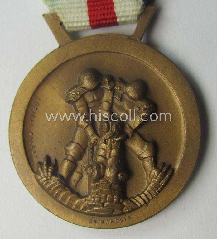 Golden-bronze-coloured- (and I deem 'Buntmetall'-based-) example of a: 'Deutsch-Italienische Feldzugsmedaille' (or: German-Italian campaign-medal) that comes mounted onto its (regular-sized) piece of original (and somewhat faded!) ribbon