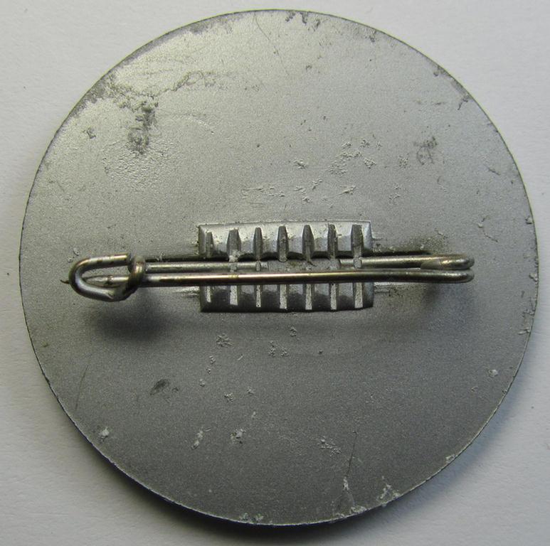 Dutch NSB-party-related, lapel-pin (ie. 'Veranstaltungsabzeichen' ie. tinnie) that is executed in silver-toned- (ie. aluminium-based-) pot-metal and that is depicting the text: 'Werkersbijeenkomst - 22/10.38 - R.A.I. - A'dam'