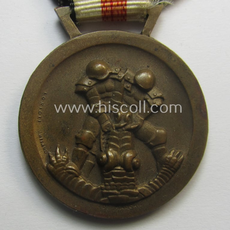 Golden-bronze-coloured- (and I deem 'Buntmetall'-based-) example of a: 'Deutsch-Italienische Feldzugsmedaille' (or: German-Italian campaign-medal) that comes mounted onto its (regular-sized) piece of original (and somewhat faded!) ribbon