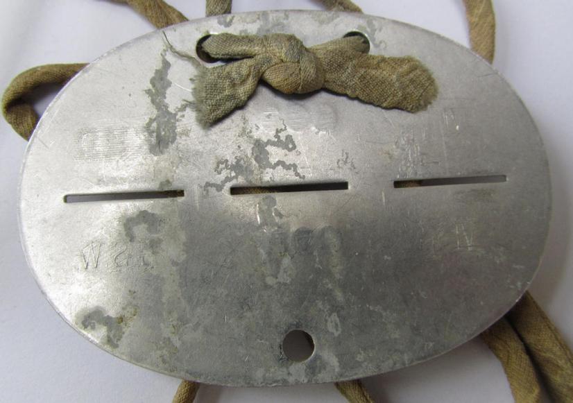Aluminium-based, 'S.H.D.'- (ie. 'Sicherheits- u. Hilfsdienst'-) related ID-disc that comes mounted on its original cord as issued and/or worn, bearing the neatly stamped unit-signification that reads: 'VI 11 491 S.H.D.'