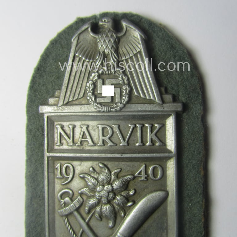 Superb - and scarcely encountered! - WH (KM) 'Narvik'-campaign-shield being a very detailed example as executed in silver-toned zinc- (ie. 'Feinzink') and that comes in an issued- (albeit I deem never worn- nor tunic-attached-), condition