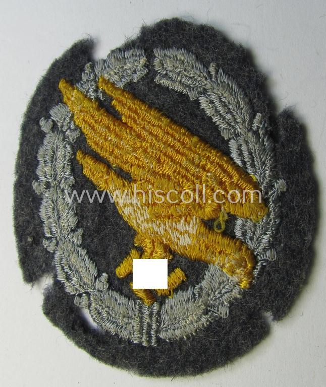 WH (Luftwaffe) 'Fallschirmschützen-Abzeichen in Stoff' (or: cloth-based paratroopers'-jump-badge) being a nicely machine-embroidered specimen that comes in a probably issued albeit (I deem) never used- ie. 'virtually mint', condition