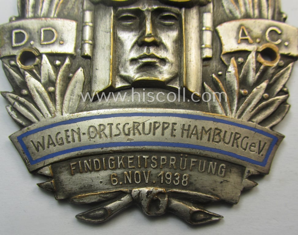 Commemorative D.D.A.C.-related car-plaque (ie. 'Erinnerungs- o. nichttragbare Kfz-plakette') showing a driver (in 'Art Deco'-style) wearing a helmet and text: 'Wagen-Ortsgruppe Hamburg e.V. - Findigkeitsprüfung - 6. Nov. 1938'