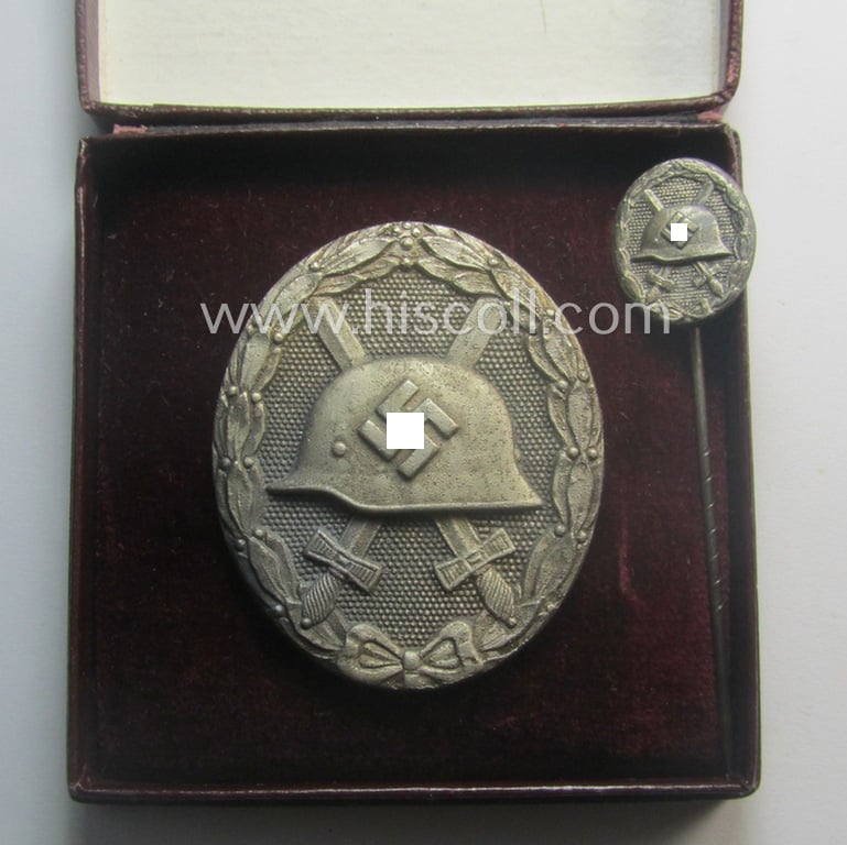Complete, silver-class wound-badge- (or: 'Verwundeten-Abzeichen in Silber'-) set comprising of a maker- (ie. '65'-) marked example (and miniature!) as produced by the 'Hersteller' ie. maker: 'Klein u. Quenzer'