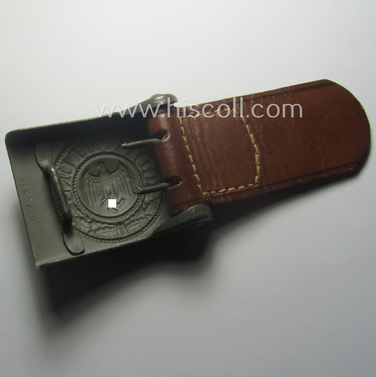 WH (Heeres) 'standard-pattern', field-grey-toned- and steel-based belt-buckle being a maker- (ie. 'Berg u. Nolte - Lüdenscheid'-) marked- and/or: '1942'-dated example that comes mounted onto its leather-based tab