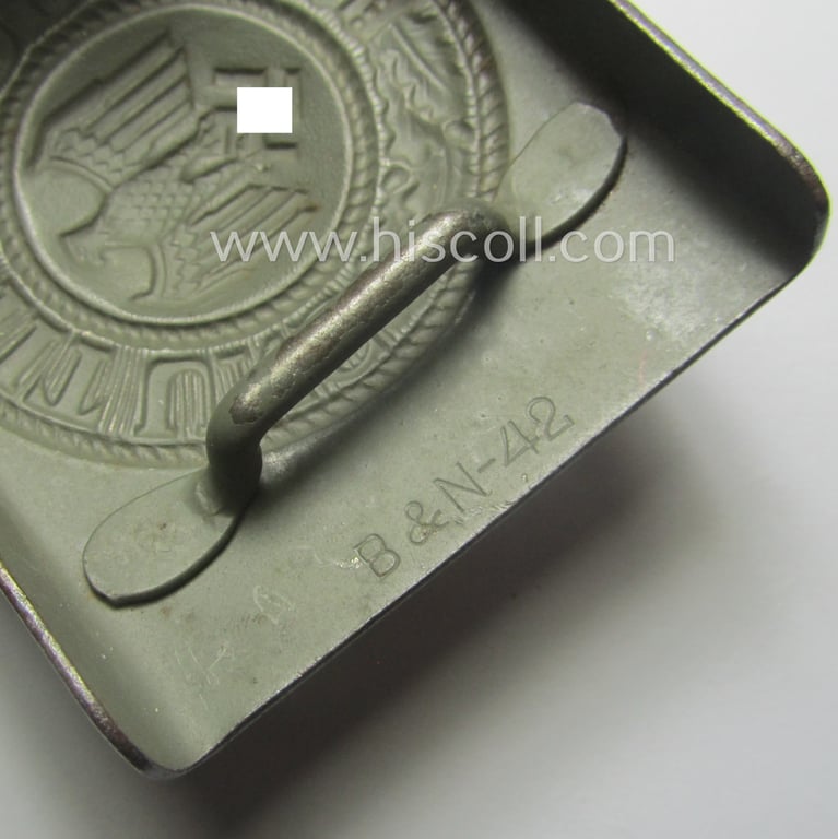 WH (Heeres) 'standard-pattern', field-grey-toned- and steel-based belt-buckle being a maker- (ie. 'Berg u. Nolte - Lüdenscheid'-) marked- and/or: '1942'-dated example that comes mounted onto its leather-based tab