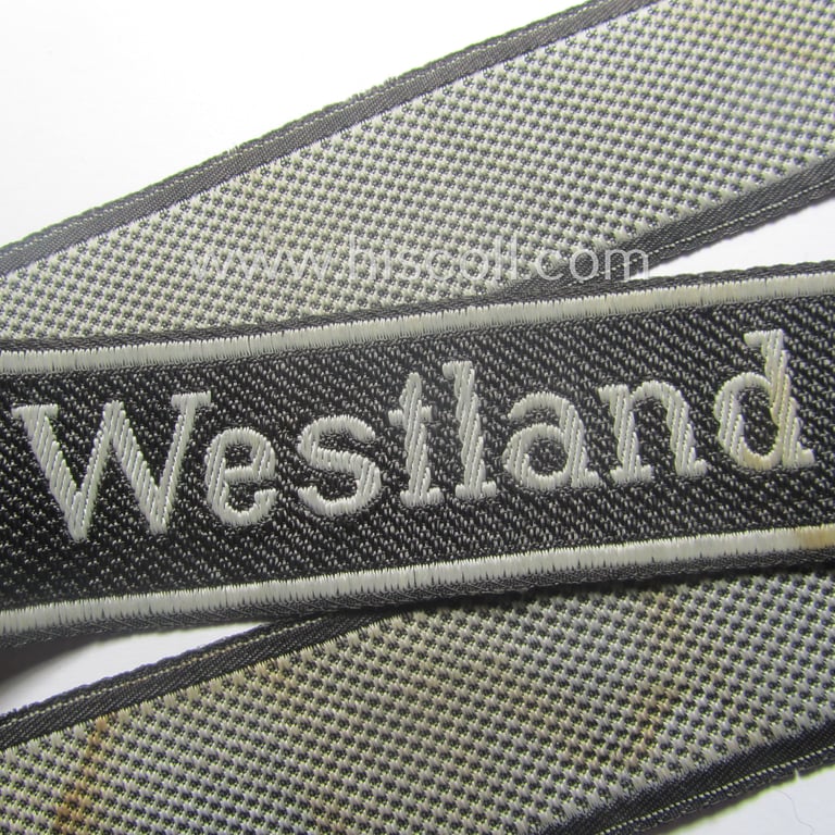 Waffen-SS, 1943/44 pattern cuff-title (ie. 'Ärmelstreifen') depicting the machine-woven Latin script text in silver-grey linnen as was intended for a member of the: 'SS-Regiment': "Westland" (ie. part of the: '5. SS-Pz-Gren.-Div. "Wiking")
