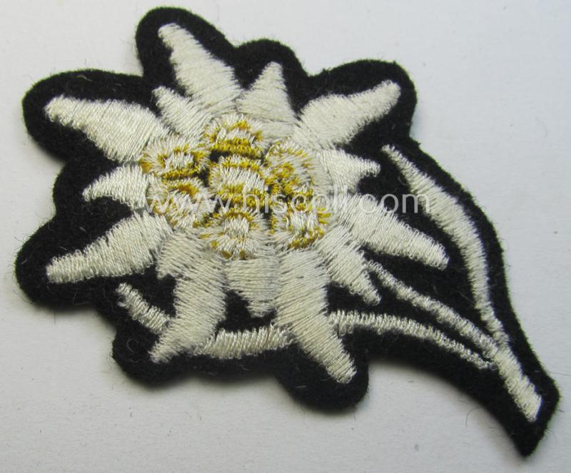 Waffen-SS-pattern, black-coloured M43-cap-insignia (ie. 'Mützenabzeichen') depicting an: 'Edelweiss'-flower as used by the various 'Gebirgsjäger'- (ie. mountain-troops-) related divisional-staff