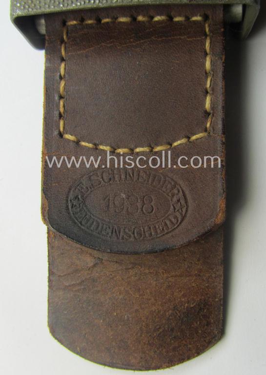WH (Heeres) 'standard-pattern', field-grey-toned- and aluminium-based belt-buckle being a maker- (ie. 'E. Schneider - Lüdenscheid'-) marked- and/or: '1938'-dated example that comes mounted onto its leather-based tab