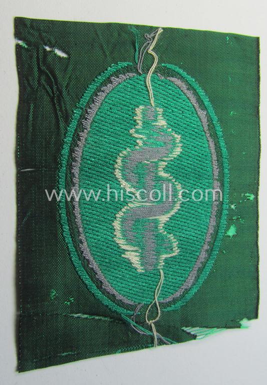 Attractive, 'Sicherheits- u. Hilfsdienst' (ie. 'SHD'-) armbadge (ie. 'Ärmelabzeichen') being a greyish-coloured example depicting an: 'Aesculapus'-symbol as was intended for a: 'Feldscher' (ie. medical SHD-staff-member)