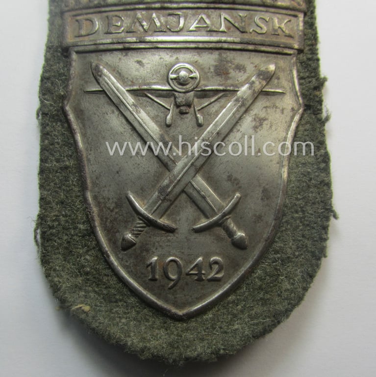 Truly used and/or worn, WH (Heeres ie. Waffen-SS) 'Demjansk'-campaign-shield (of the 'missing log'-pattern) as executed in typical magnetic metal (ie. so-called: 'Eisenblech') and that comes in an overall nice- (ie. fully untouched!), condition