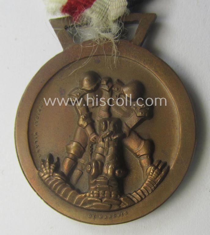 Golden-bronze-coloured- (and I deem 'Buntmetall'-based-) example of a: 'Deutsch-Italienische Feldzugsmedaille' (or: German-Italian campaign-medal) that comes mounted onto its (regular-sized) piece of original (and sun-faded!) ribbon