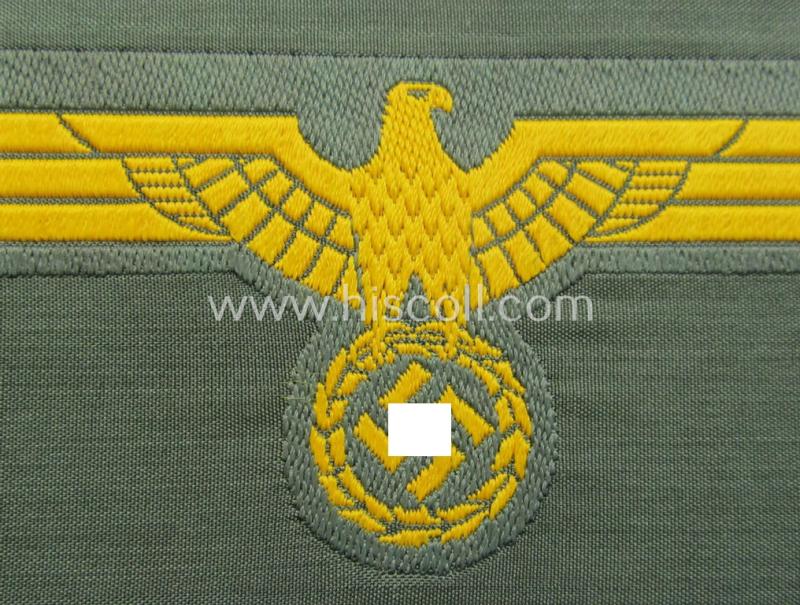 WH (Kriegsmarine) ie. 'Küst.-Art.'-related breast-eagle (ie. 'Brustadler für Mannschaften u. Uffz. der Küsten-Artillerie-Truppen') being a 'standard-issue'-pattern-example as executed in the 'BeVo'-weave-pattern on a field-grey-coloured backg...