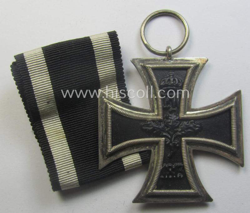 WWI-period: 'Eisernes Kreuz II. Klasse' (or: iron cross second class) being a maker- (ie. 'KO'-) marked example that comes together with its (minimally) confectioned piece of ribbon (ie. 'Bandabschnitt')