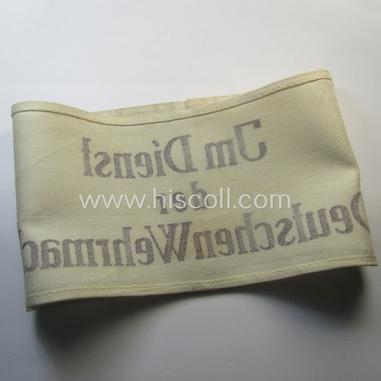 Linnen-based- and/or neatly printed, white-coloured armband (ie. 'Armbinde') entitled: 'Im Dienst der Deutsche Wehrmacht' as was intended for (civilian) staff-members serving within the German armed forces ie. 'Deutsche Wehrmacht'