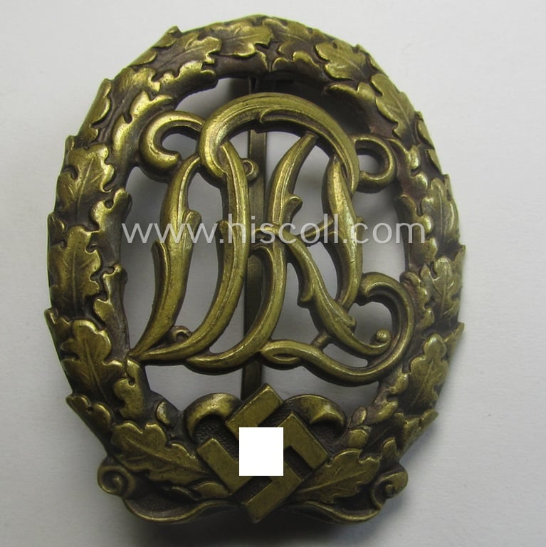 'Reichssportabzeichen DRL in Bronze' (or: bronze class DRL sports'-badge) being a maker- (ie. 'Ernst L. Müller'-) marked and that comes with its accompanying miniature