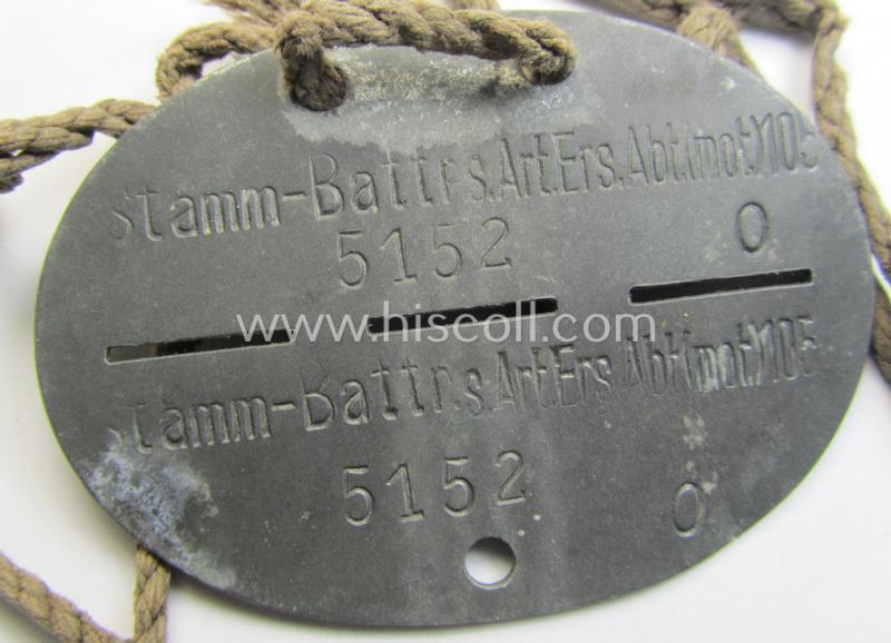 Zinc-based, WH (Heeres) ie. 'schwere Artillerie'-related ID-disc bearing the clearly stamped unit-designation: 'Stamm-Battr.s.Art.Ers.Abt.(mot) 105' and that comes mounted onto its period cord as issued and worn