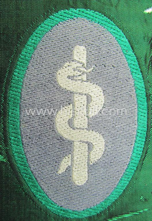 Attractive, 'Sicherheits- u. Hilfsdienst' (ie. 'SHD'-) armbadge (ie. 'Ärmelabzeichen') being a greyish-coloured example depicting an: 'Aesculapus'-symbol as was intended for a: 'Feldscher' (ie. medical SHD-staff-member)