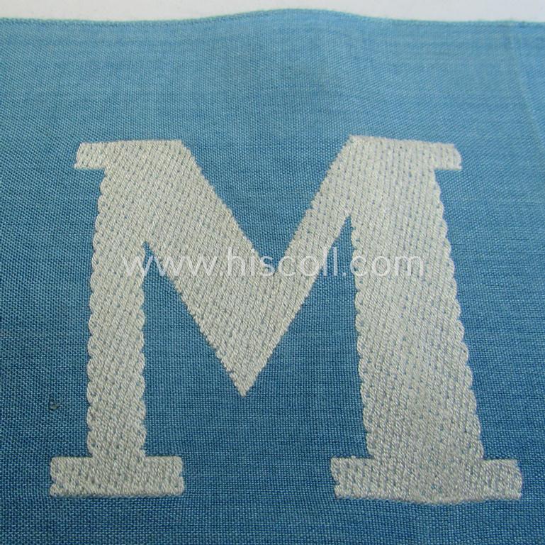 Attractive, linnen-based- and/or light-blue-coloured armband (ie. 'Armbinde') depicting an interwoven capital 'M'-character as was presumably intended for staff-members of the German RLB (ie. 'Reichsluftschutz-Bund')