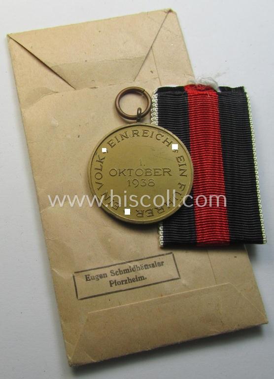Superb, WH Czech occupation-medal '1 October 1938' and accompanying (mint- & non-confectioned) ribbon (ie. 'Bandabschnitt') that comes stored in its original, carton-based pouch as was produced by the maker: 'Eugen Schmidhäussler'