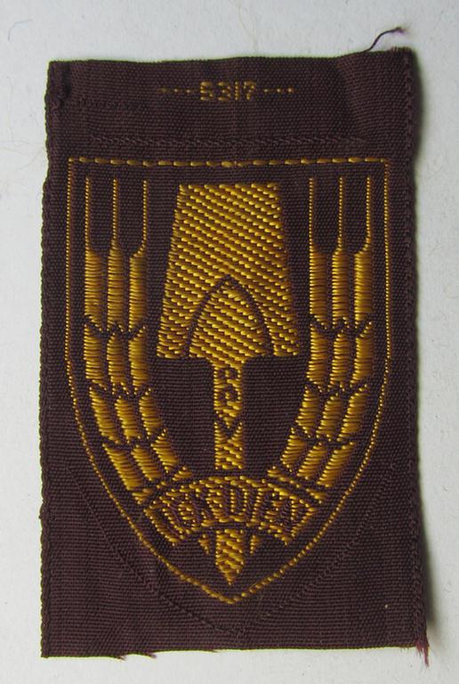 Neat - and nicely 'BeVo-woven'-like - Dutch WWII-period, labour service ie. 'Nederlandse Arbeidsdienst' (or: NAD) cap-badge entitled: 'Ick Dien' and that comes in a 'virtually mint- ie. unissued', condition
